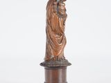 a statue of a woman holding a child on top of a wooden base