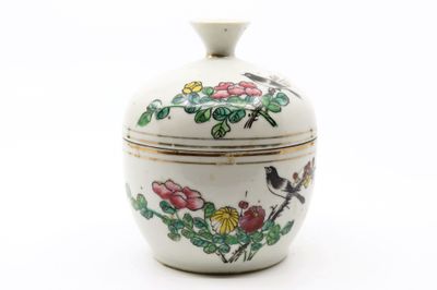un petit vase blanc orné d'un oiseau et de fleurs