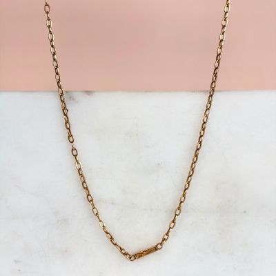 une photo du collier à chaîne en or posé sur une surface en marbre