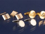 trois paires de boutons de manchette en or et une paire de boutons de manchette en argent sur un fond bleu