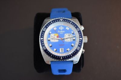 a close up of a blue watch on a black surface