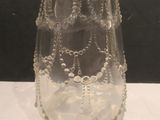 a glass vase with beads on it sitting on a table
