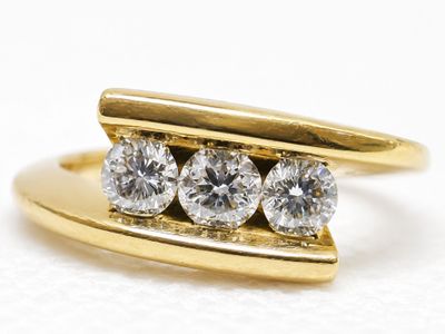 an image of a three stone diamond ring on a white surface