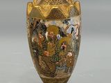 a gold vase with a painting on it sitting on a table