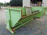 a green dumpster sitting in the middle of a gravel lot