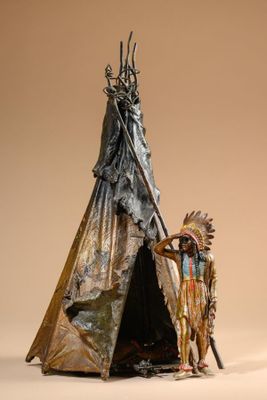 statue of a native american indian standing next to a teepee