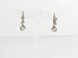 boucles d'oreilles plaquées argent ornées de cristaux, présentées sur un présentoir transparent
