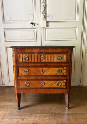 une petite commode en bois posée sur un parquet en bois massif