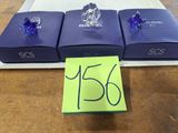 trois boîtes bleues ornées de cristaux violets et bleus, posées sur une table