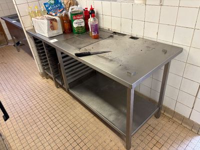 une table de travail en acier inoxydable sur laquelle est posé un couteau