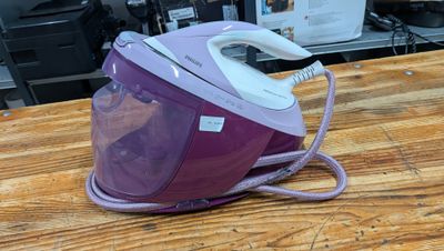 purple and white steam iron sitting on top of a wooden table