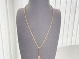 necklace on a mannequin with a gold chain and a diamond pendant
