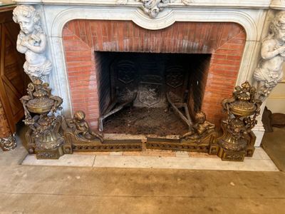 une cheminée au milieu d'une pièce, avec des statues sur le manteau de cheminée
