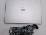 a laptop computer sitting on a table with a charger attached to it