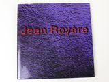un gros plan sur un livre violet sur lequel figure le nom « Jean Royère »