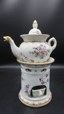 a white tea pot with a gold rim and a tea cup on it