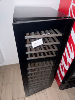 a black refrigerator with a sign on it next to a coke machine