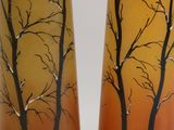 two tall vases with trees painted on them