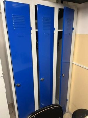 blue lockers in a bathroom with a toilet and a trash can