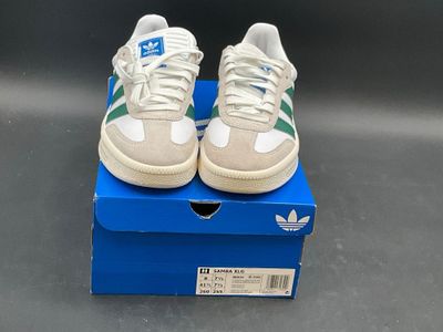 adidas superstar shoes in a box on a grey surface