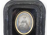 an old picture of a woman in a black dress in a black frame