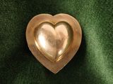 a gold heart shaped brooch on a green cloth