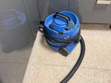 a blue vacuum sitting on the floor next to a cabinet