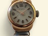 une montre-bracelet argentée et dorée posée sur une surface blanche
