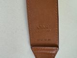 the back of a brown leather bag with a metal clasp