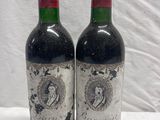 two bottles of red wine sitting on top of a white table