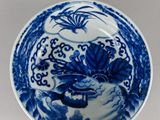 a blue and white plate with a bird and flowers on it