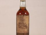 an old bottle of whiskey sitting on top of a white table