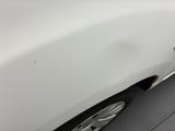 the front bumper of a white car with a dent on it