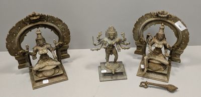 trois figurines en bronze représentant des divinités hindoues, posées sur des socles sur une table