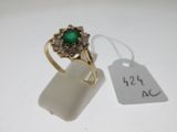 gros plan d'une bague en or avec une pierre verte