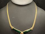 a green and gold necklace on a mannequin mannequin
