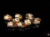 some gold colored beads on a black surface with a black background