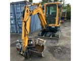 an image of a yellow excavator parked in front of a shipping container