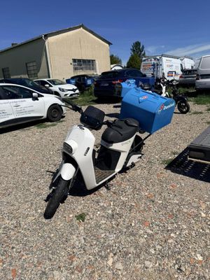 un scooter garé sur un parking, avec d'autres véhicules en arrière-plan