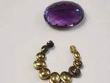 a close up of a bracelet and a purple stone on a white surface