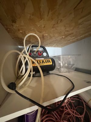 a small air compressor sitting on a shelf with a bunch of wires
