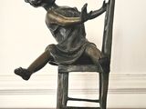 une statue en bronze représentant un enfant assis sur une chaise