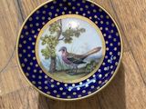 a plate with a bird painted on it sitting on a table