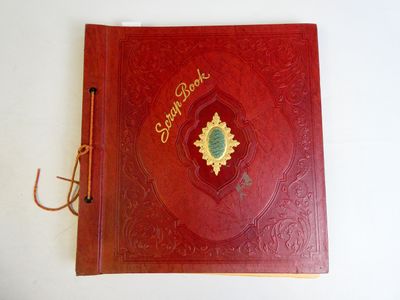 un vieux livre rouge sur lequel repose un stylo, posé sur une surface blanche