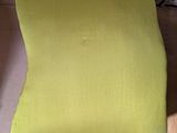 a yellow cushion on a wooden table next to a stack of books