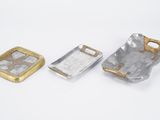 two pieces of silver and gold metal on a white surface