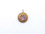 un gros plan d'un pendentif en or orné d'une pierre violette