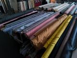 many rolls of fabric sitting on a rack in a room