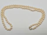 a close up of a pearl necklace on a white surface