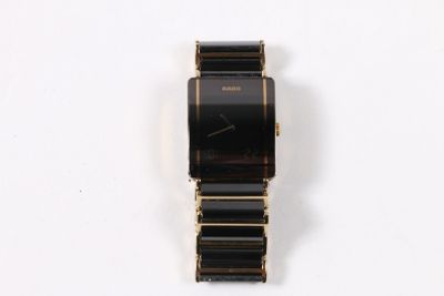 l'image d'une montre noire et or sur une surface blanche